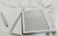 an e-reader and a pen on a bed