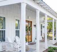 a white porch with striped chairs and a porch swing
