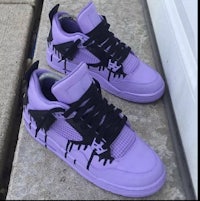 a pair of purple air jordan 4's with black dripping paint